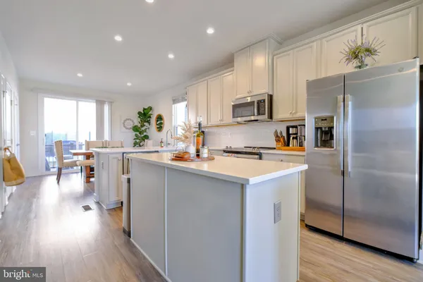 a kitchen with stainless steel appliances a refrigerator a stove a sink dishwasher and a refrigerator with wooden floor