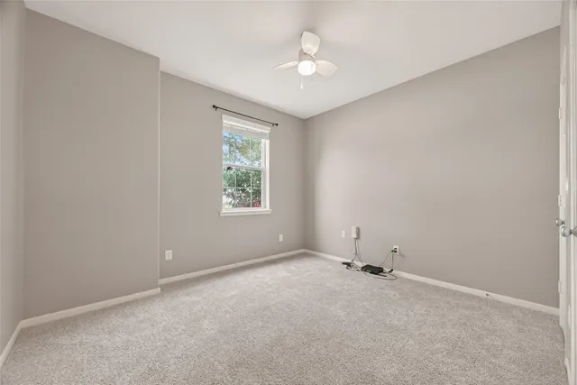 an empty room with a window and a fan