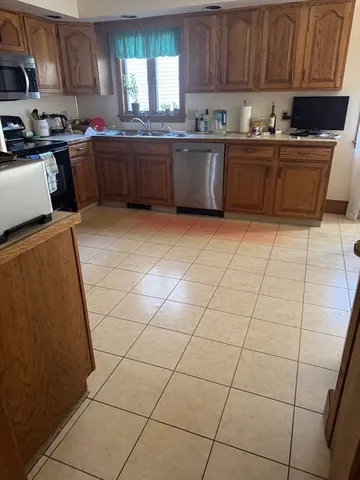 a kitchen with granite countertop a stove a sink a counter top space and cabinets
