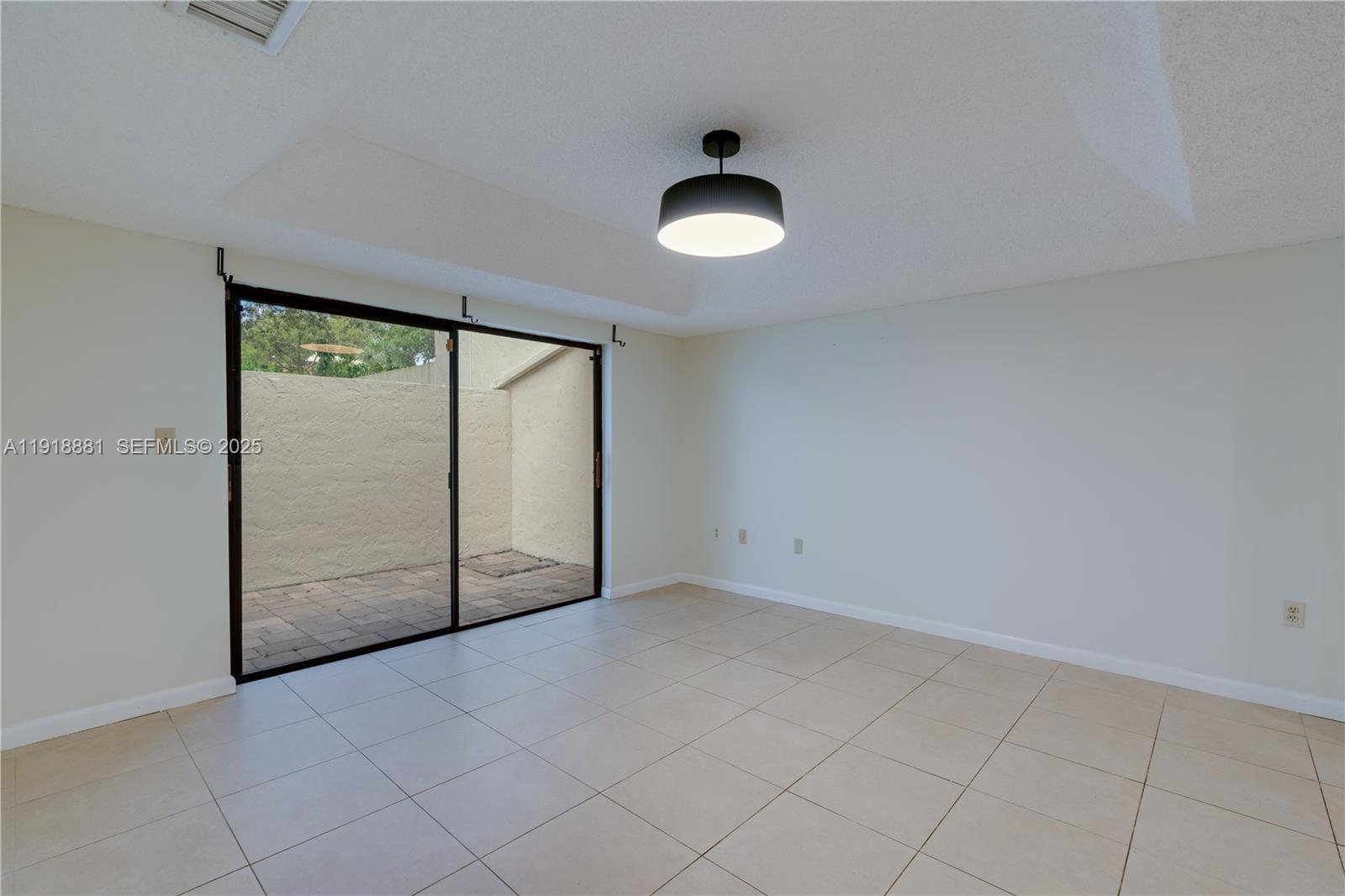7827 Southwest 106th Circle, Unit 7827 Miami, FL 33173 - Photo 8 of 23 an empty room with a large window and chandelier fan