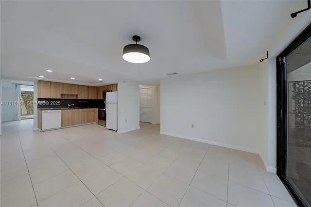 a view of a electric appliances in kitchen and empty room with wooden floor