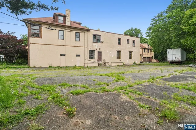 a view of a white house with a big yard with large trees