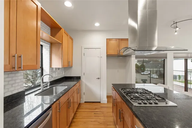 a kitchen with stainless steel appliances kitchen island granite countertop a dining table chairs and granite counter tops