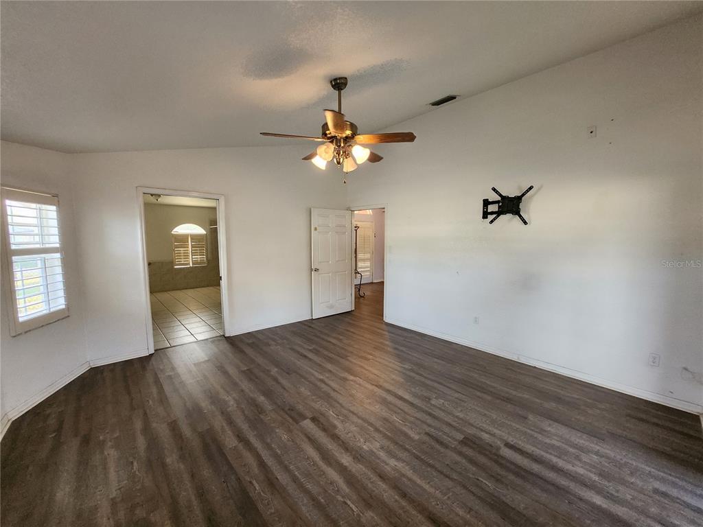 23104 Rountree Avenue Port Charlotte, FL 33980 - Photo 18 of 41 a view of an empty room with wooden floor and a ceiling fan