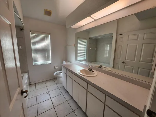 a bathroom with a sink a toilet a mirror and shower