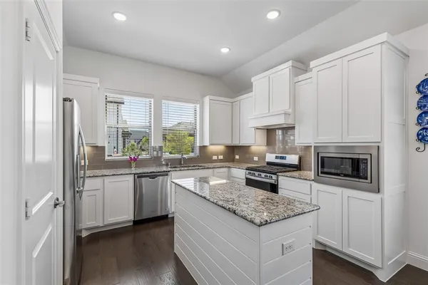 a kitchen with stainless steel appliances granite countertop a stove a sink and a refrigerator