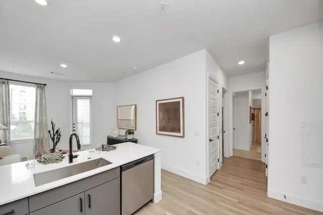 a living room with stainless steel appliances furniture and a kitchen view