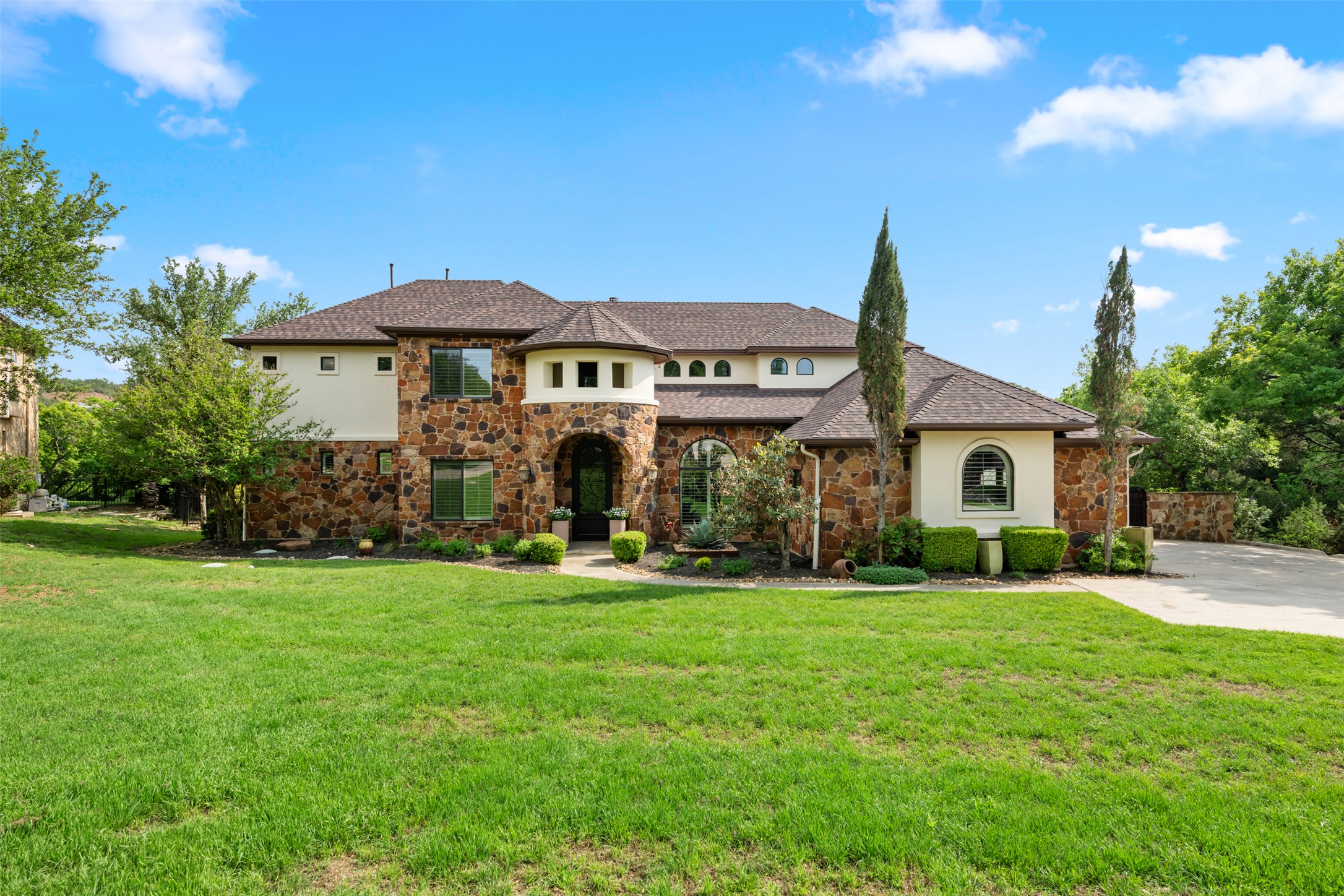 The property features a stone and stucco exterior, a prominent curved entry, and a well-maintained lawn