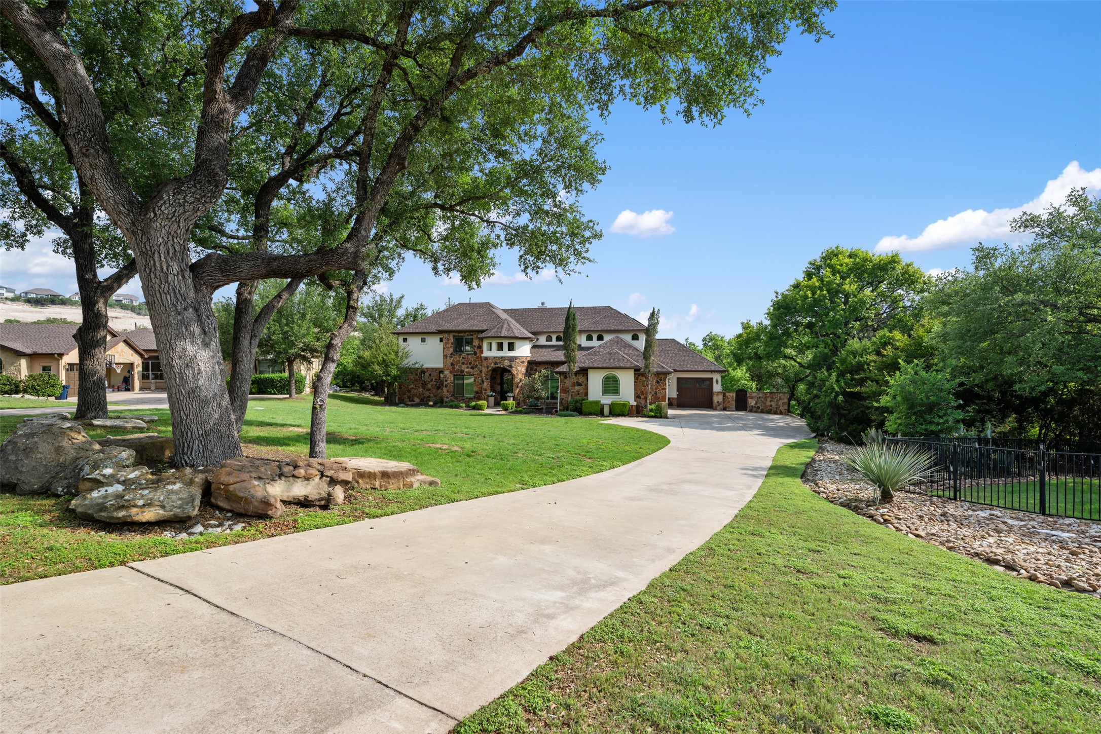 1102 Paw Print Leander, TX 78641 - Photo 2 of 40 The property features a concrete driveway leading to the main residence, with a well-maintained lawn and mature trees