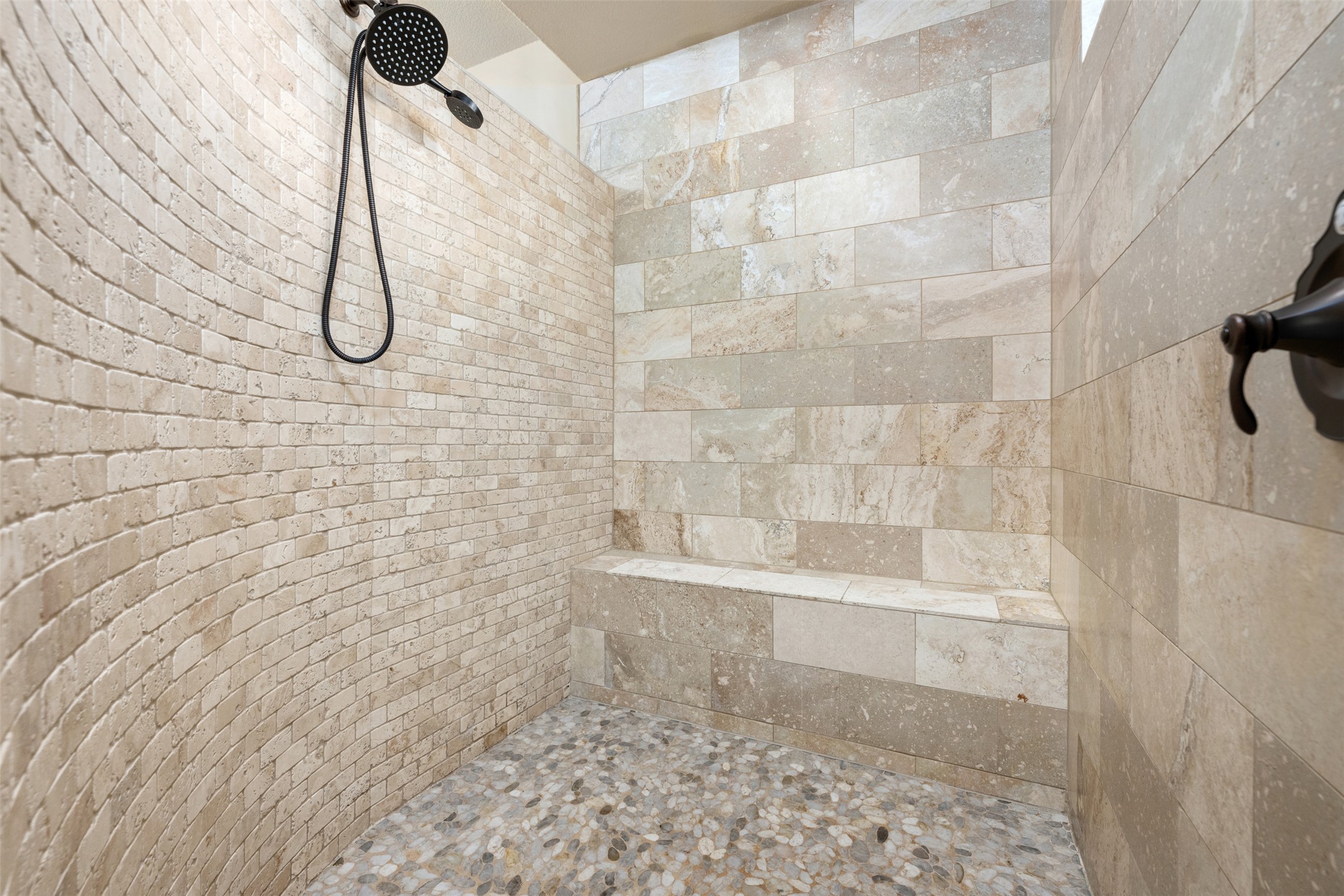 1102 Paw Print Leander, TX 78641 - Photo 24 of 40 Shower featuring a curved brick-patterned wall, a built-in bench, and a pebbled floor