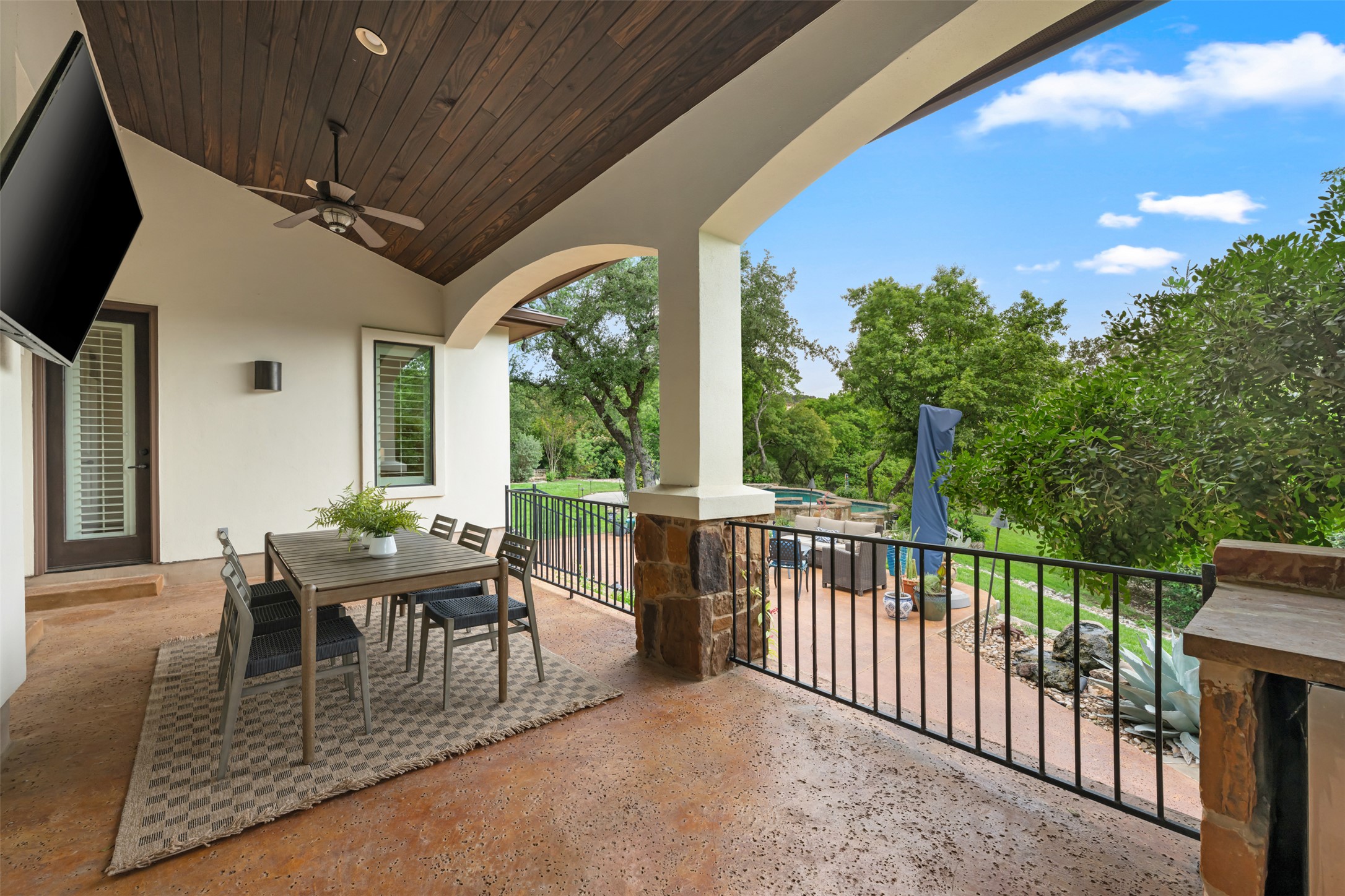 1102 Paw Print Leander, TX 78641 - Photo 28 of 40 Expansive covered patio featuring a wood-paneled ceiling with a ceiling fan, a stone column, and a black metal railing overlooking the outdoor space