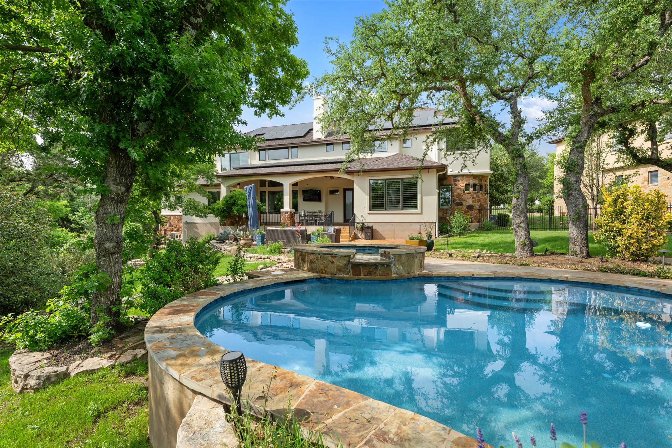 1102 Paw Print Leander, TX 78641 - Photo 32 of 40 This property features an inviting swimming pool with stone coping and a spa, surrounded by a lush green lawn and mature trees