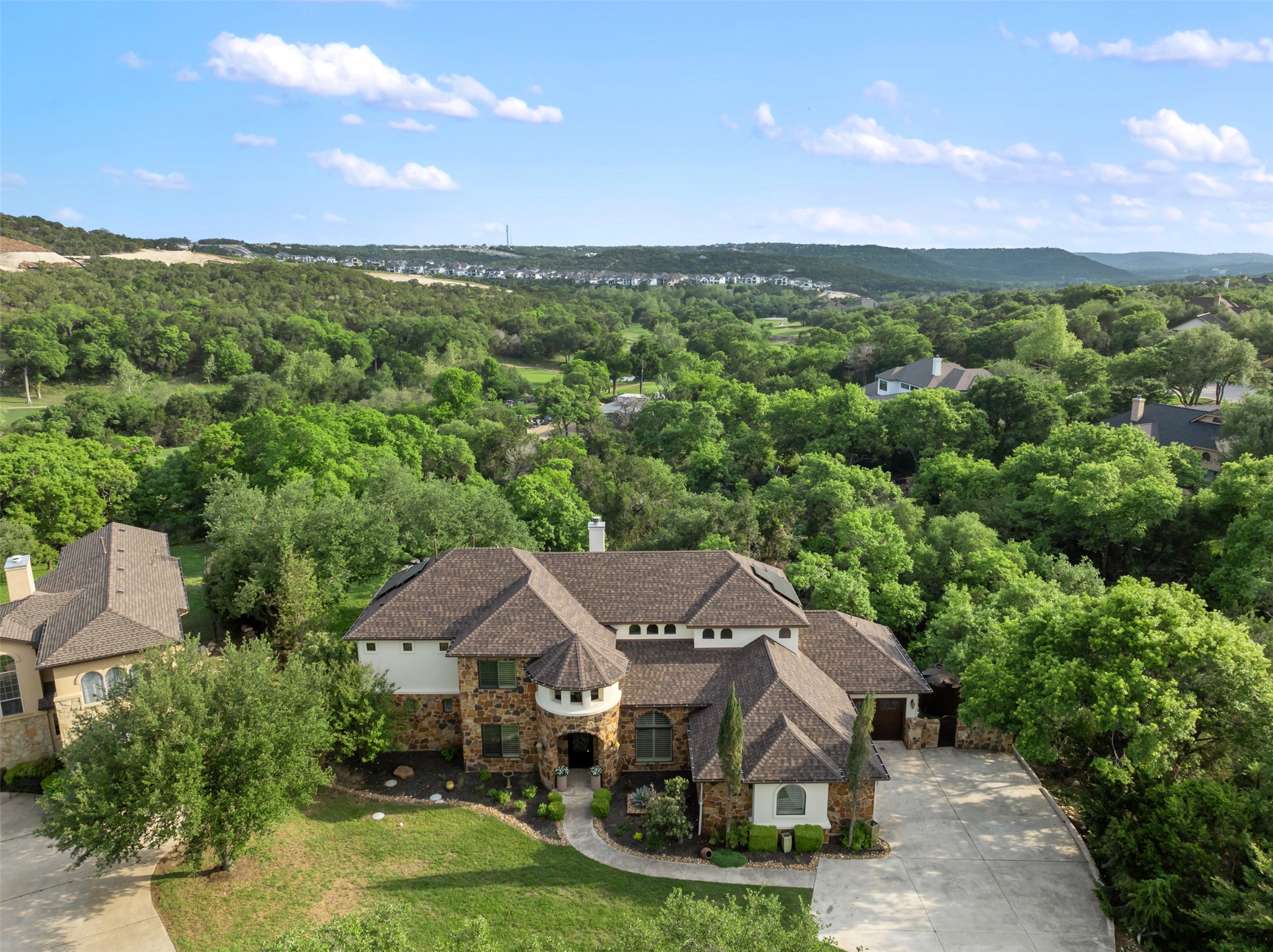 1102 Paw Print Leander, TX 78641 - Photo 33 of 40 The property features an extensive stone and stucco exterior, a prominent turretted entrance, and a paved driveway leading to a two-car garage