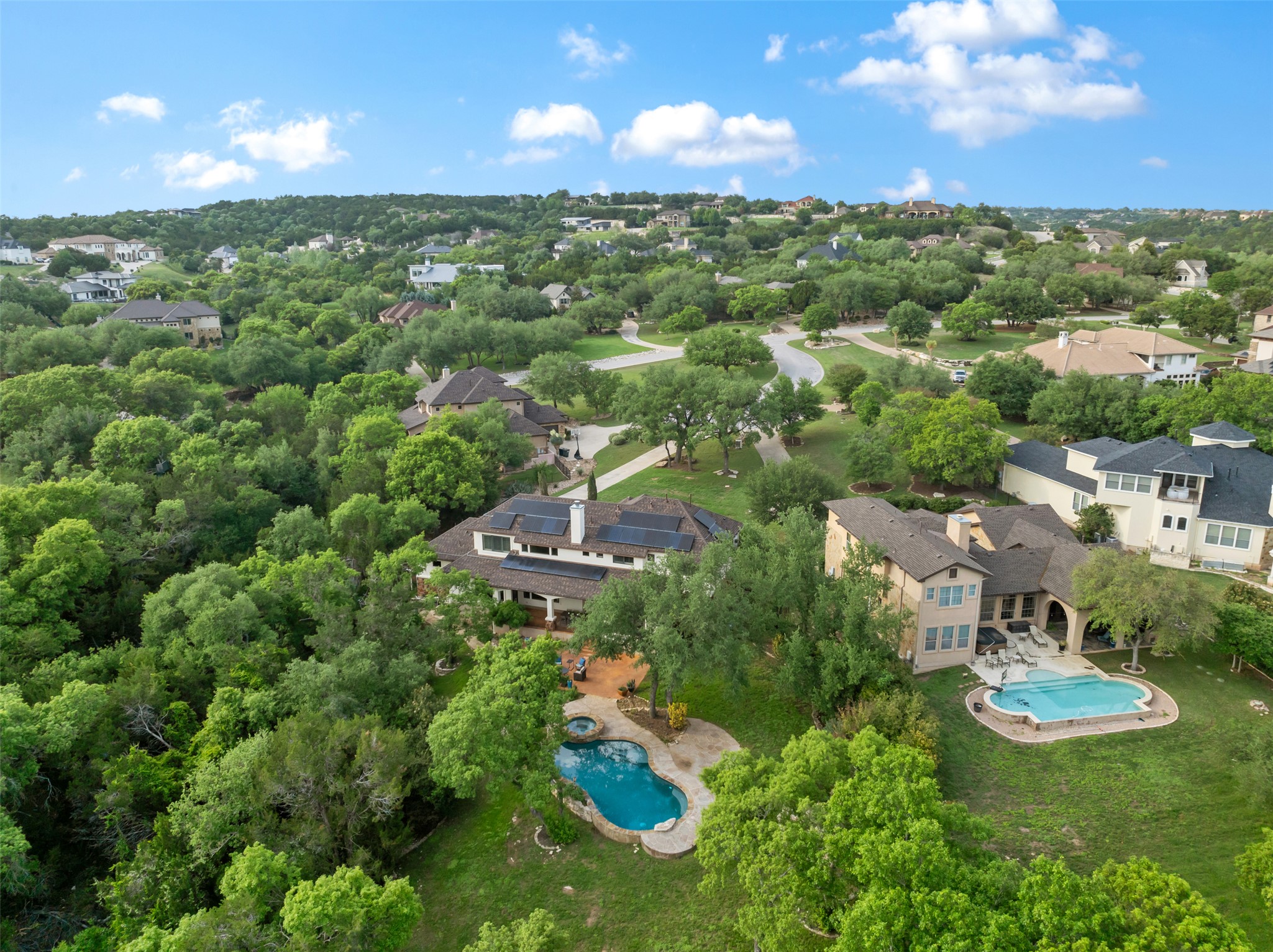 1102 Paw Print Leander, TX 78641 - Photo 35 of 40 This expansive property features two distinct outdoor swimming pools, surrounded by mature trees and lush green landscaping