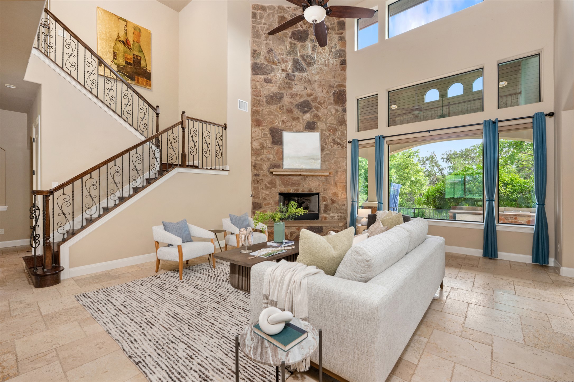 1102 Paw Print Leander, TX 78641 - Photo 10 of 40 The living area features high ceilings, a stone fireplace, and large windows providing natural light and views of greenery