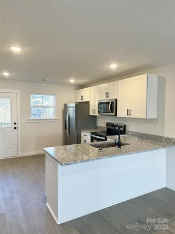 a kitchen with stainless steel appliances granite countertop a sink a stove and a granite counter top
