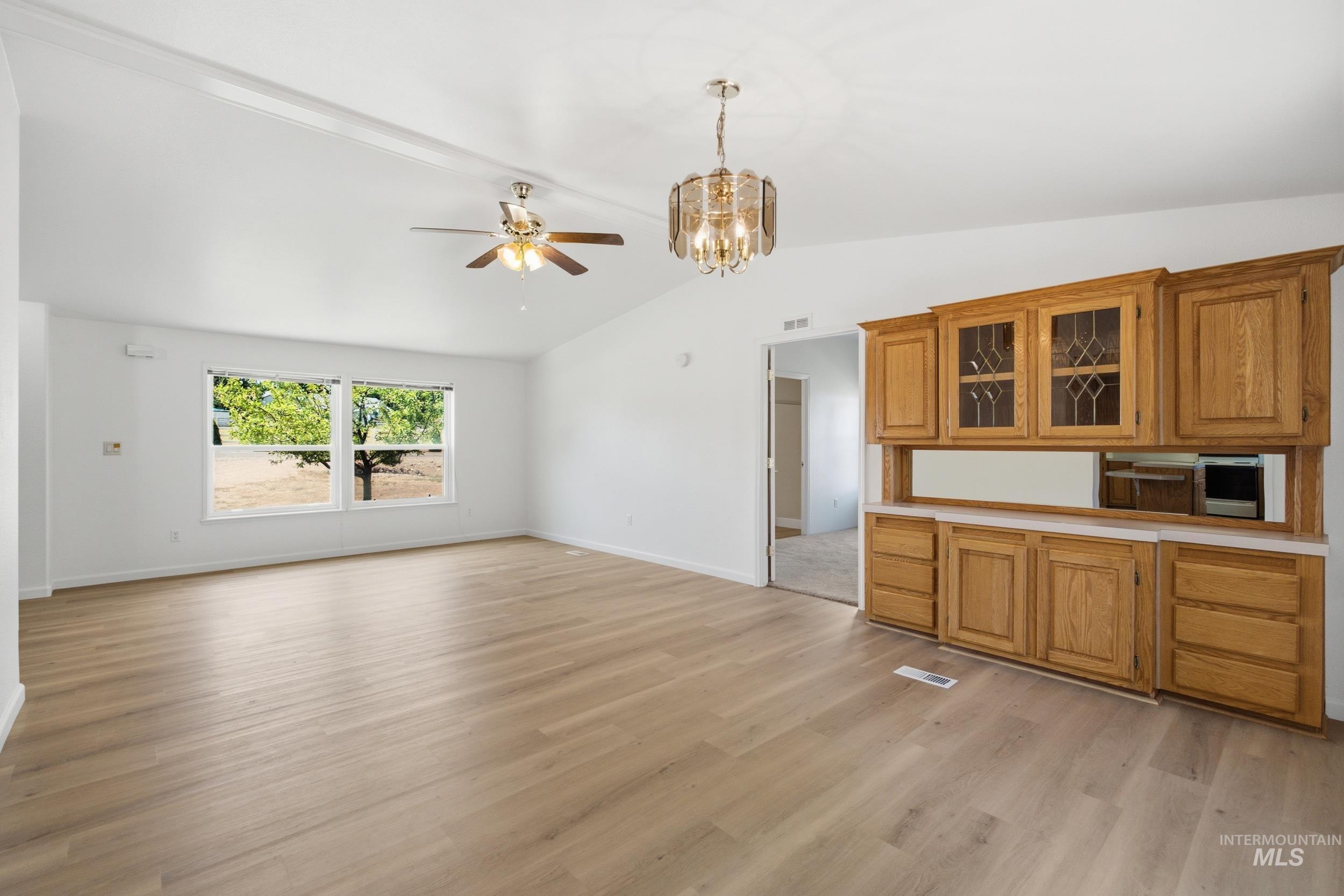 7422 Track Road Nampa, ID 83686 - Photo 16 of 50 Spacious room featuring vaulted ceilings, light wood-finish flooring, and a built-in wood cabinetry unit with glass-front display cabinets