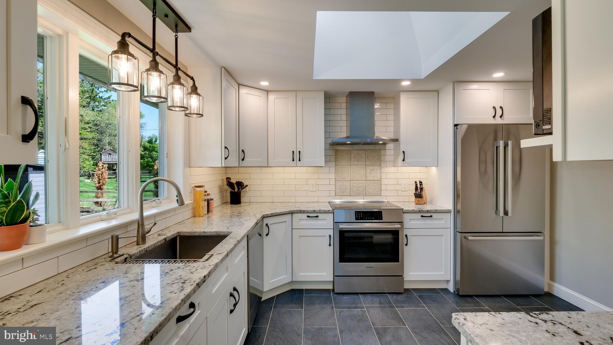 235 North Clinton Street Doylestown, PA 18901 - Photo 19 of 55 a kitchen with stainless steel appliances granite countertop a refrigerator a sink a stove and white cabinets with wooden floor
