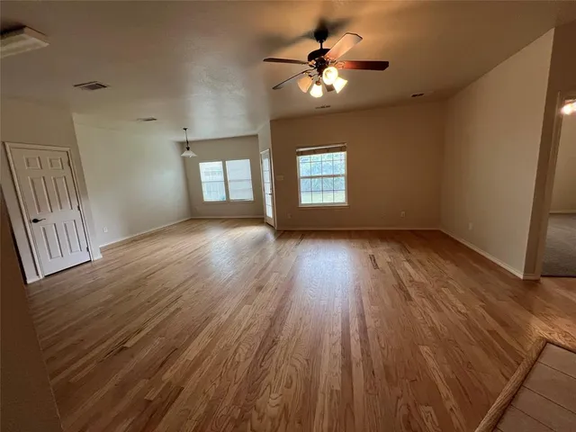 a view of an empty room with a window and wooden floor