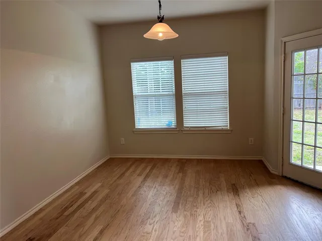 an empty room with wooden floor windows and cabinet
