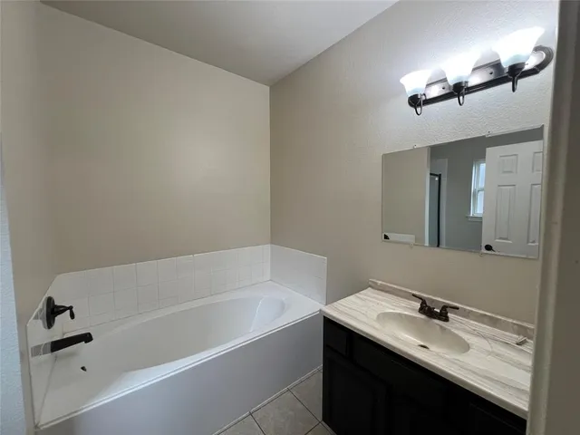 a bathroom with a tub a sink and mirror