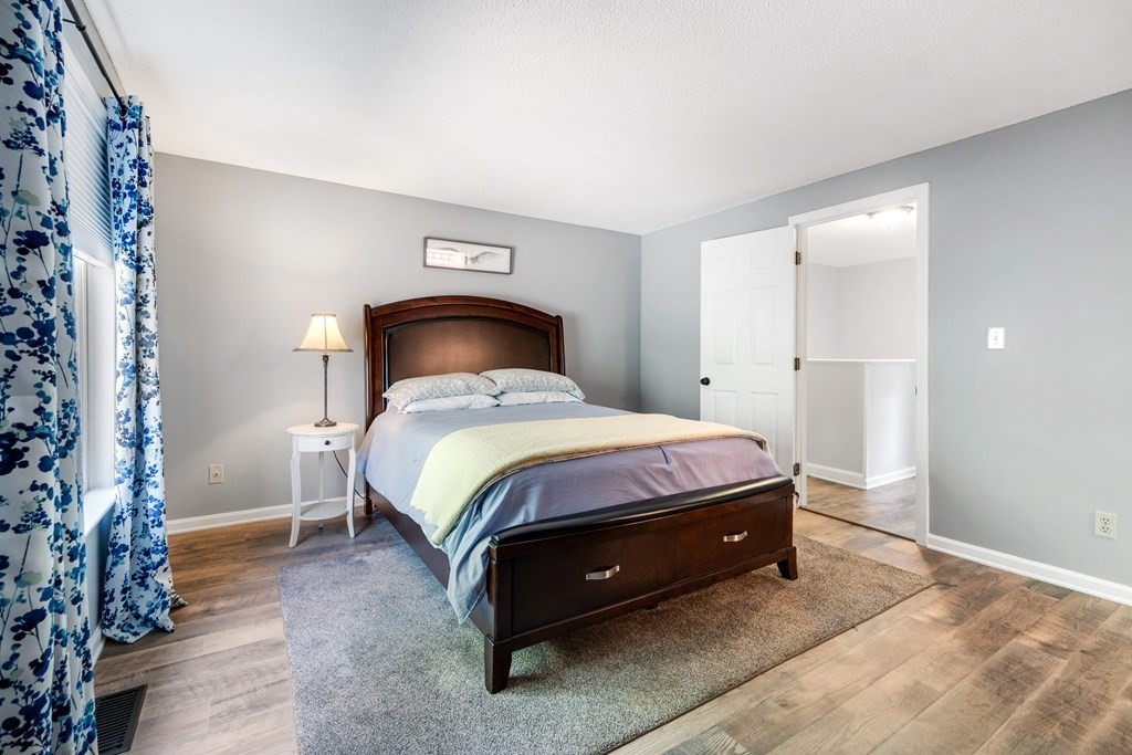 55 Stone Ridge Road, Unit 55 Franklin, MA 02038 - Photo 19 of 27 a bed sitting in a room next to a lamp and a window