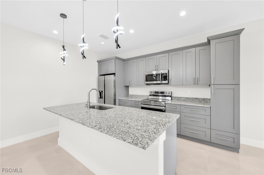 8771-8773 Buckingham Road Lehigh Acres, FL 33971 - Photo 19 of 34 a kitchen with stainless steel appliances granite countertop a sink a microwave and cabinets