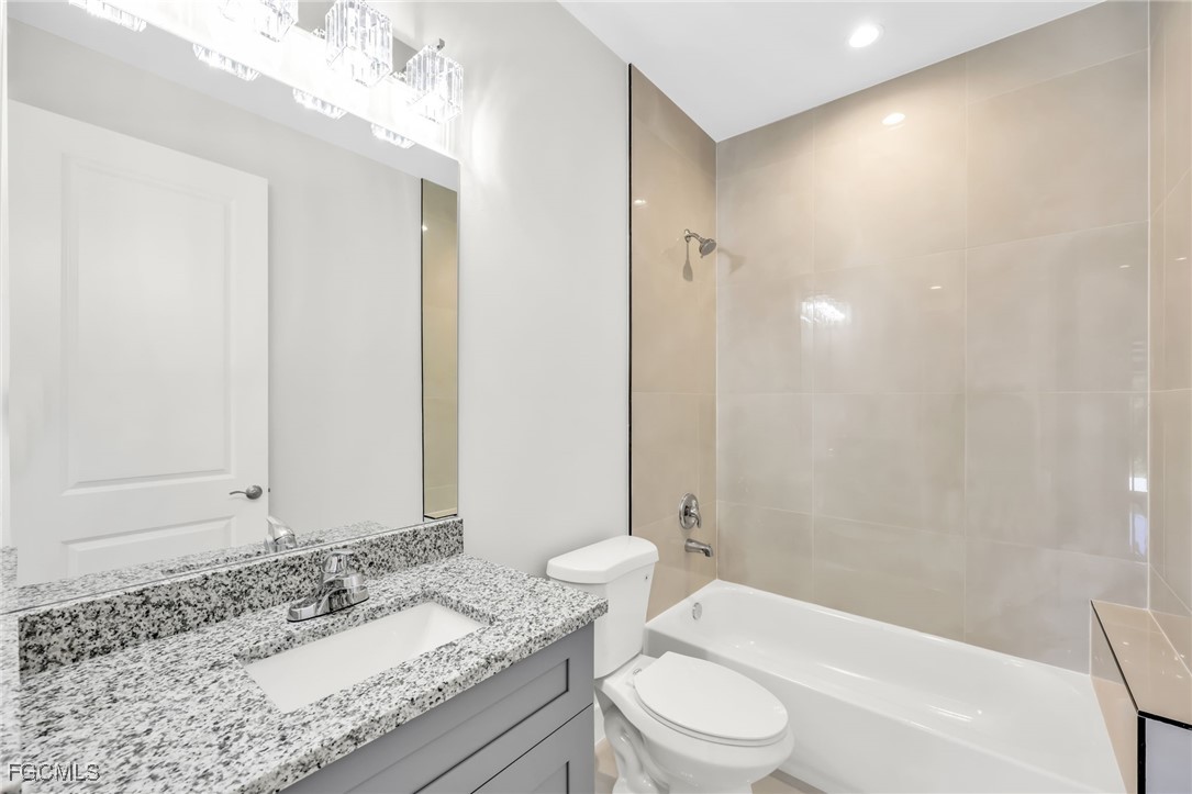 8771-8773 Buckingham Road Lehigh Acres, FL 33971 - Photo 30 of 34 a bathroom with a granite countertop sink a toilet and shower