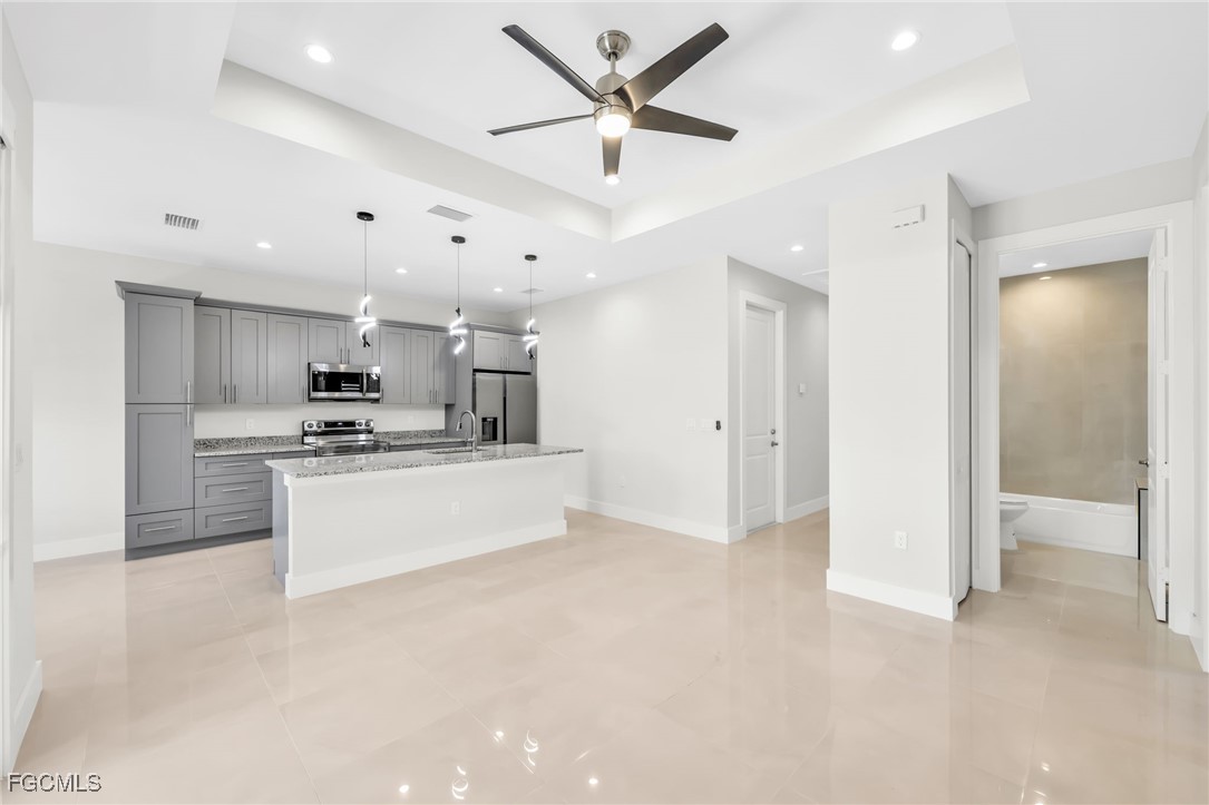 8771-8773 Buckingham Road Lehigh Acres, FL 33971 - Photo 5 of 34 a large kitchen with stainless steel appliances kitchen island a sink a refrigerator and a stove