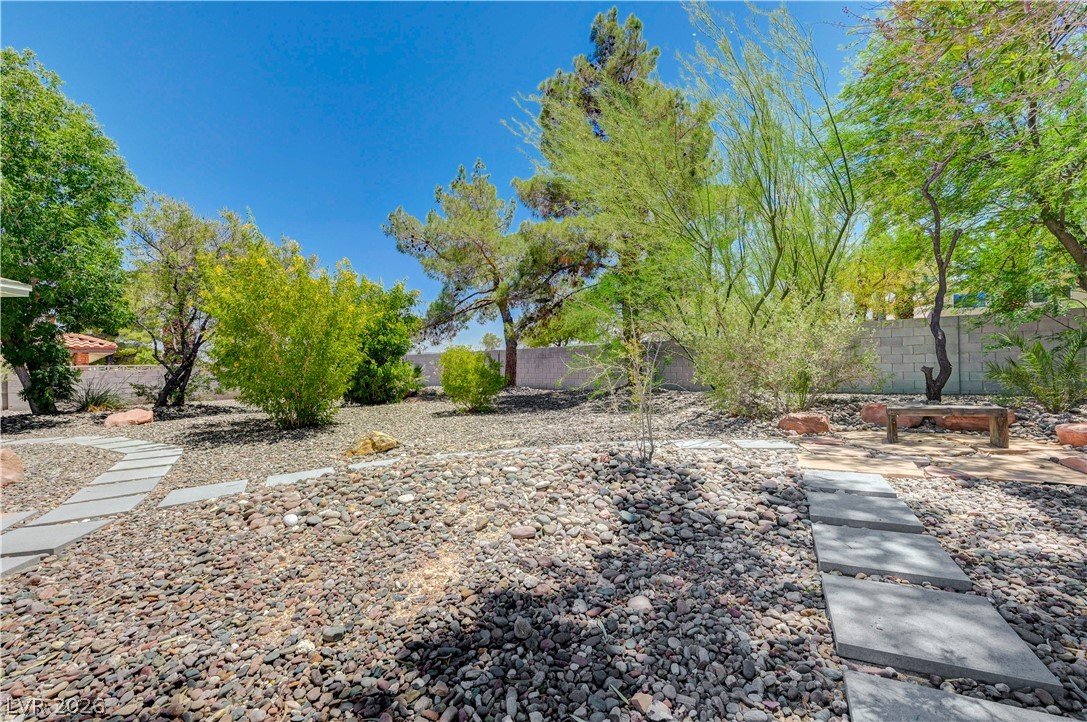 7631 Bermuda Road Las Vegas, NV 89123 - Photo 46 of 64 A tranquil desert landscape awaits with stone pathways, verdant foliage, and a peaceful seating area.