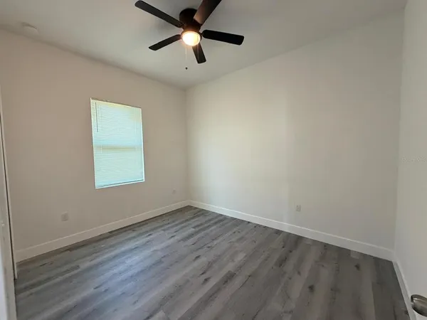 an empty room with a window and a fan