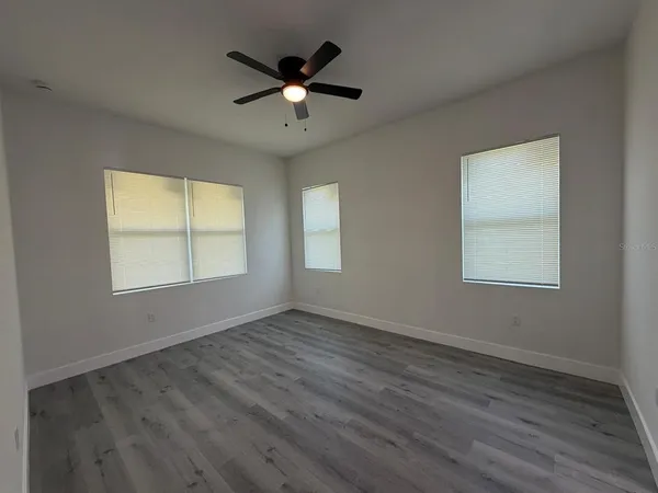 an empty room with wooden floor chandelier and windows