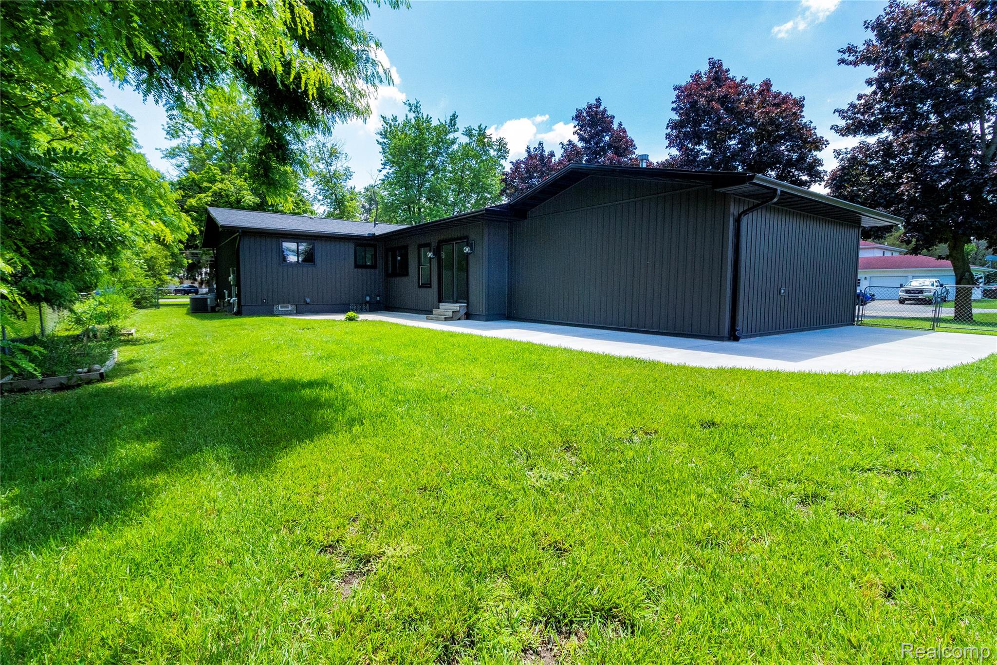 1138 Baldwin Road Lapeer, MI 48446 - Photo 46 of 49 Spacious green lawn surrounding the home's charcoal siding, featuring a substantial concrete patio and mature trees