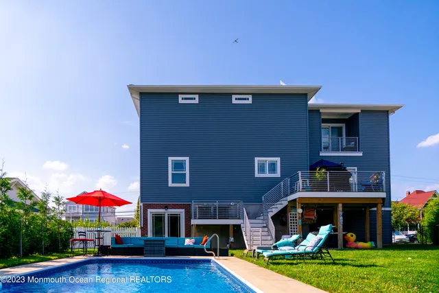 a front view of a house with swimming pool and chairs