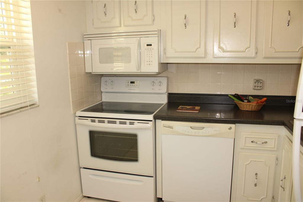 11485 Oakhurst Road, Unit 1200215 Largo, FL 33774 - Photo 17 of 68 a kitchen with granite countertop white cabinets and white appliances