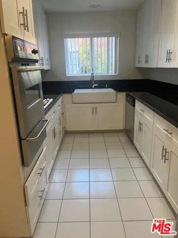 a kitchen with stainless steel appliances a sink window and cabinets