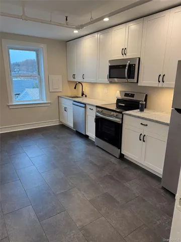 a kitchen with stainless steel appliances a stove a sink a microwave a refrigerator and cabinets