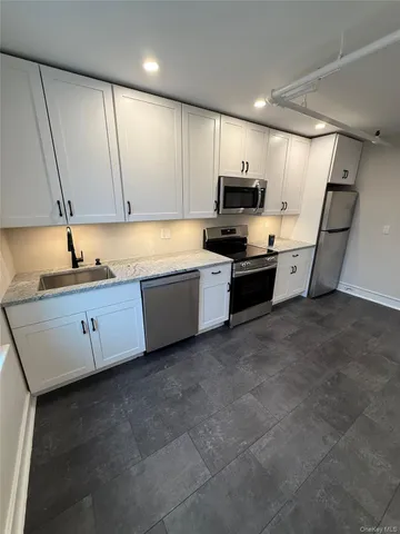 a kitchen with stainless steel appliances granite countertop a sink a stove and a refrigerator