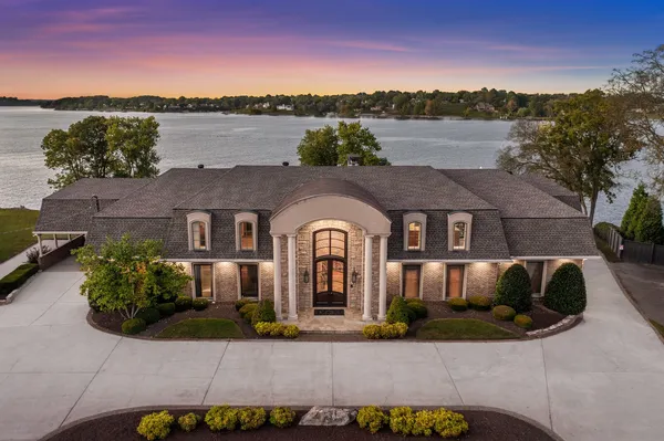 a front view of a house with a yard and lake view