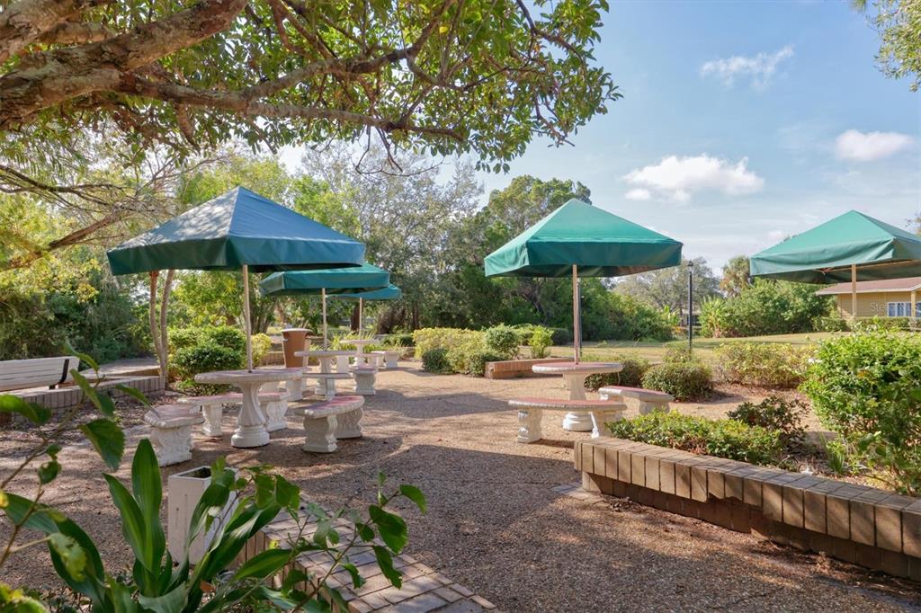 4513 Morningside, Unit 4 Sarasota, FL 34235 - Photo 44 of 81 a view of a patio with chairs and a table and chairs under an umbrella with large trees