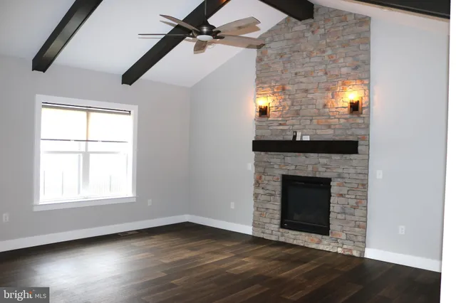 an empty room with wooden floor fireplace and windows
