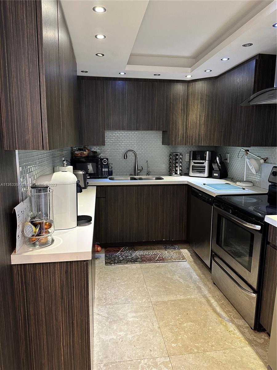 200 Southeast 15th Road, Unit 5J Miami, FL 33129 - Photo 6 of 20 a kitchen with stainless steel appliances a sink dishwasher stove top oven and cabinets