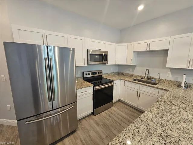 a kitchen with granite countertop stainless steel appliances a refrigerator a stove a sink a microwave and cabinets