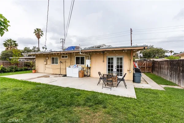 a view of a backyard with table and chairs potted plants and wooden fence