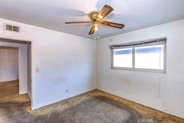 an empty room with a ceiling fan and window