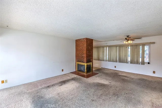 an empty room with chandelier fan and windows