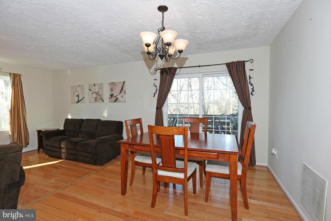 1816 Windjammer Way Gaithersburg, MD 20879 - Photo 7 of 29 a dining room with wooden floor a chandelier a glass table and chairs