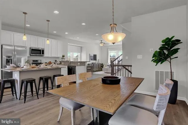 a kitchen with kitchen island a dining table chairs stainless steel appliances and cabinets