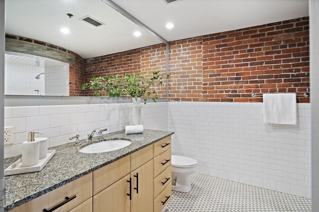 9 West Broadway, Unit 312 Boston, MA 02127 - Photo 15 of 35 a bathroom with a granite countertop sink a toilet a mirror and shower