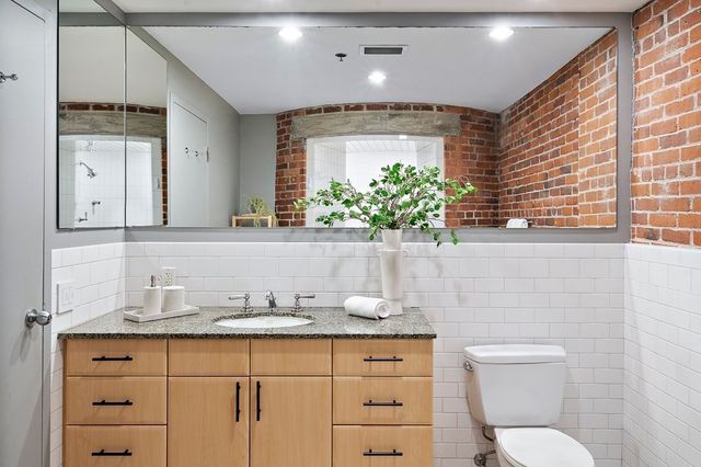 a bathroom with a granite countertop sink mirror vanity and toilet
